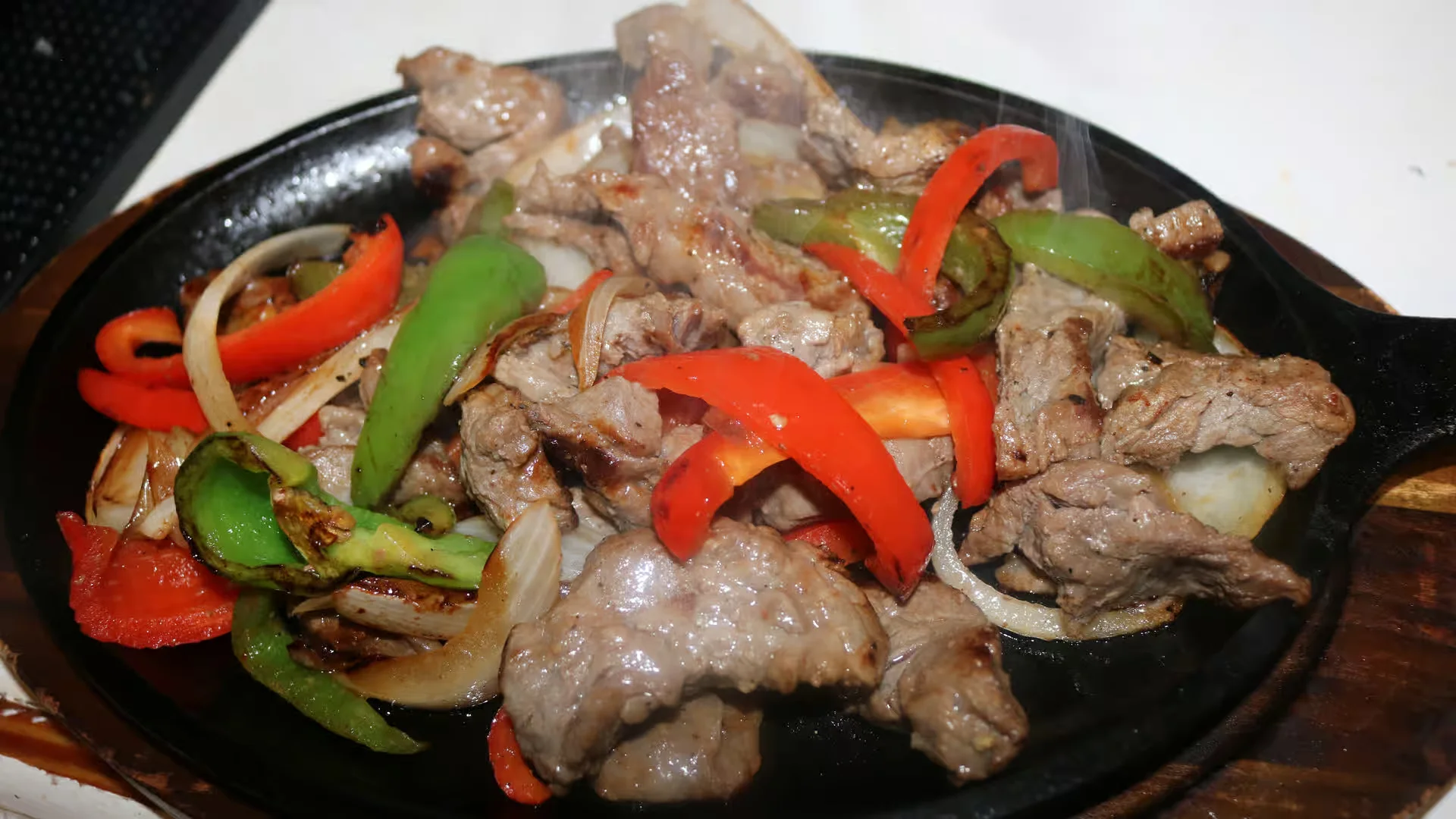 Beef & Chicken Fajita Plate - Sizzling beef and chicken fajitas served on a hot cast iron skillet with peppers, onions, rice, beans, and fresh tortillas.